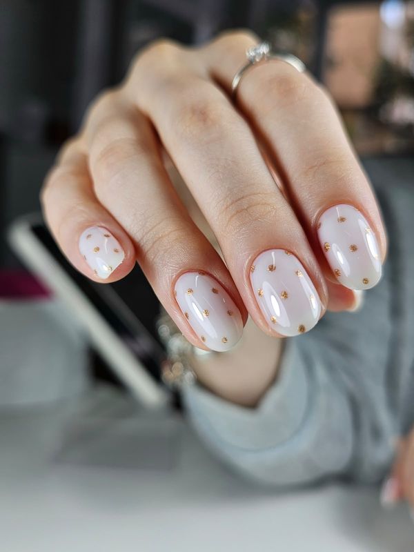 Manicura rusa con nivelación en blanco lechoso con topos dorados